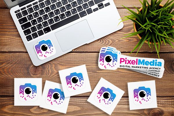 Different logo stickers scattered across a table with one on a laptop.